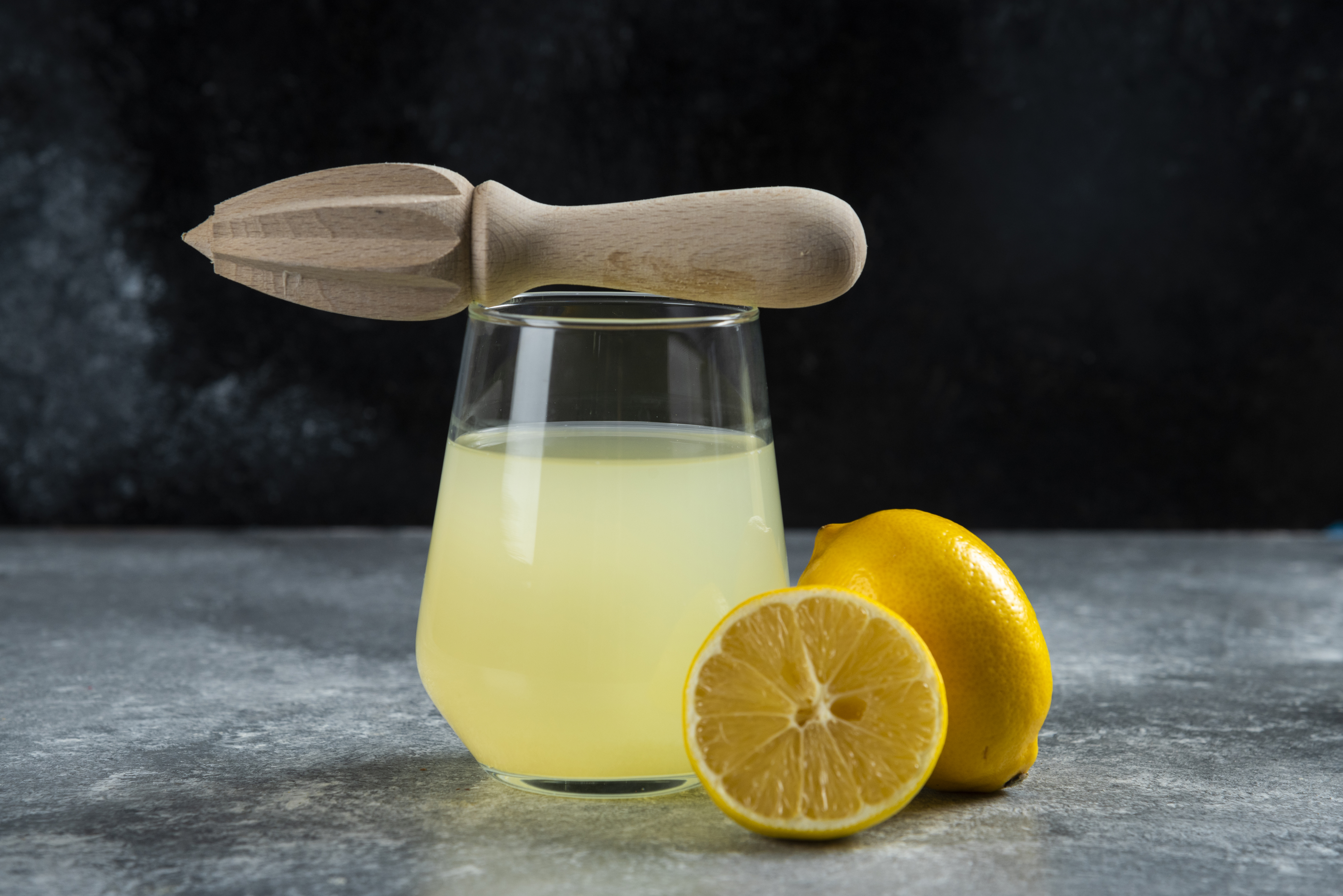 A glass cup of lemon juice and wooden reamer. High quality photo